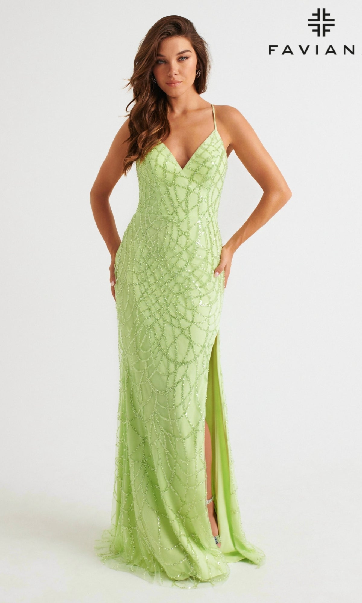A woman models the Glitter Faviana Long Strappy-Back Prom Dress 11084 in light green, featuring spaghetti straps and a thigh-high slit, against a white background. The Faviana logo is visible in the upper right corner.